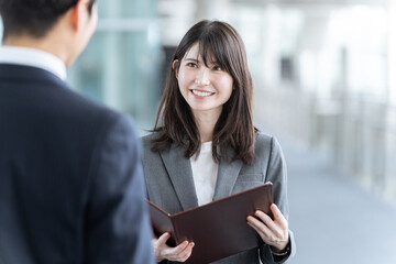 資料を抱え話す女性スタッフ